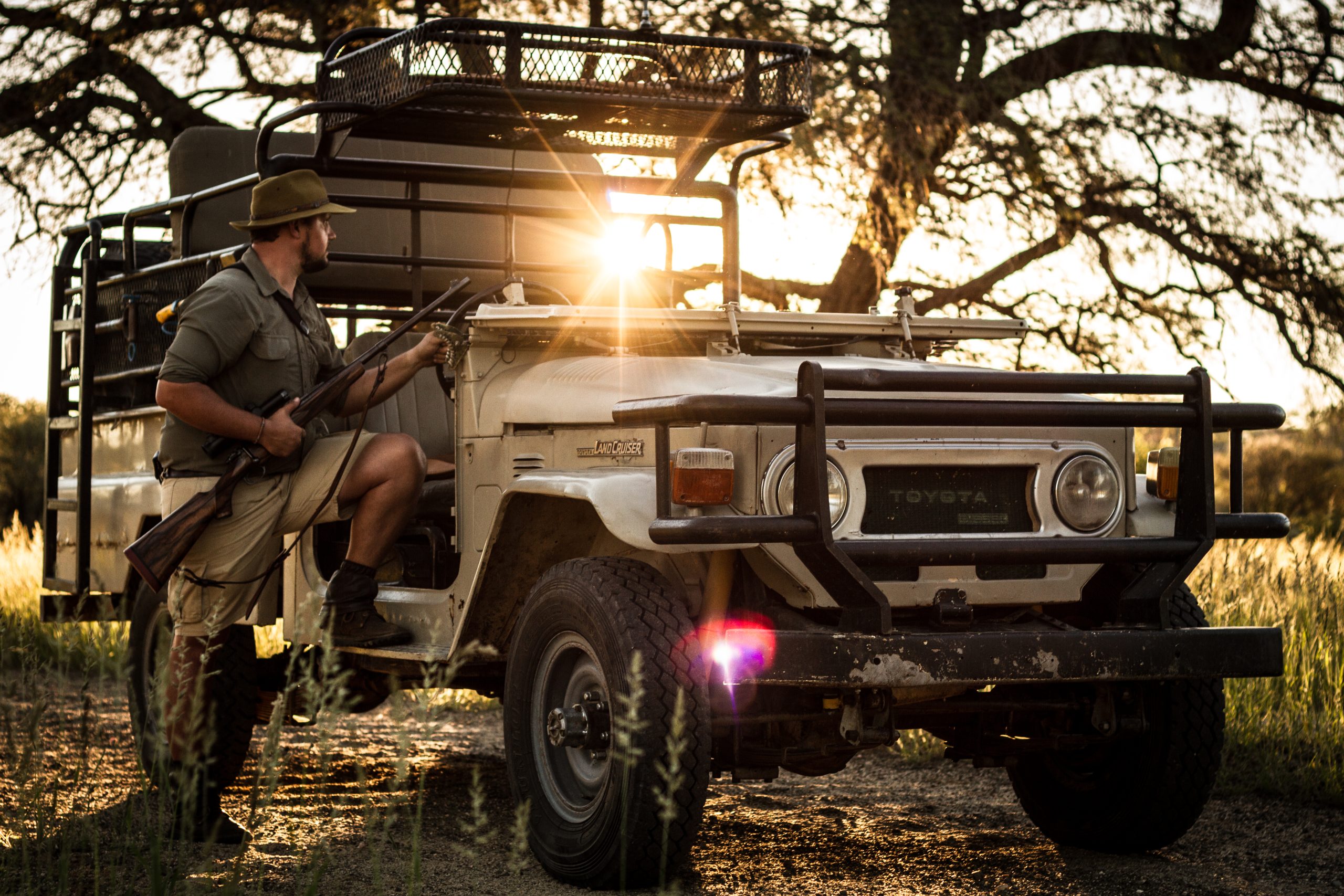 A man stepping into a 4x4 with his rifle